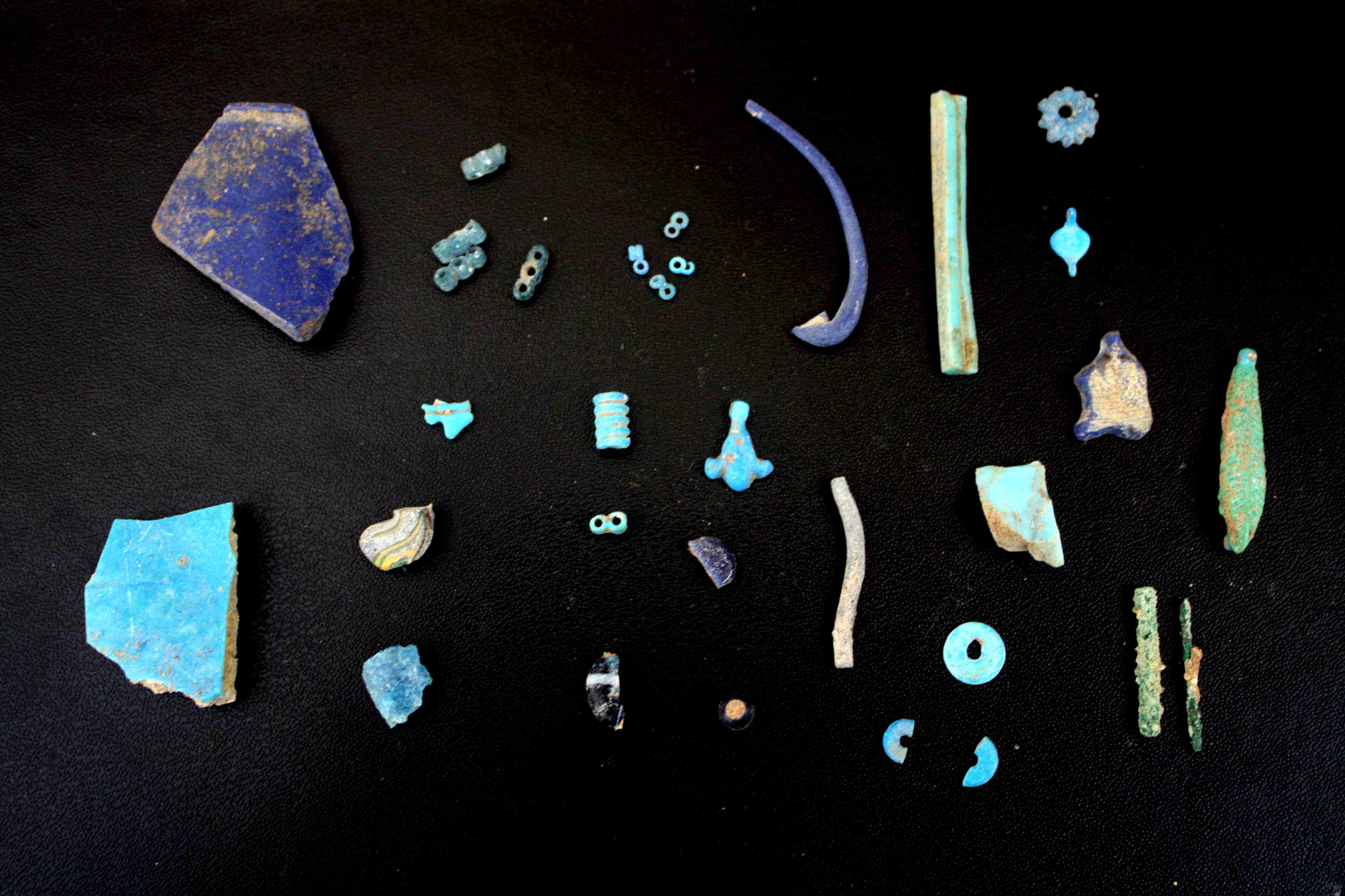 A small selection of fragments, amulets and beads from glass and faience found at Amarna M50.14-16